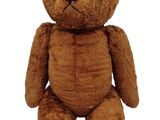 a brown teddy bear that is sitting on a white surface