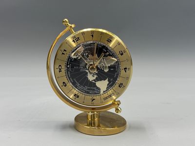 une image représentant une horloge dorée sur laquelle figure une carte du monde