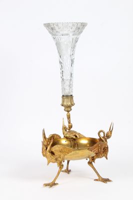 un vase en verre avec un socle doré et un animal doré représenté dessus