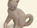 a small statue of a cat sitting on a white surface