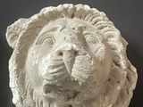 a white lion head on the wall next to a candle