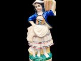 figurine représentant une femme tenant un éventail et un panier