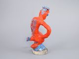 statue of a man sitting on top of a rock with a red body