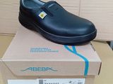 des chaussures en cuir noir avec des semelles en caoutchouc, posées sur une boîte en carton