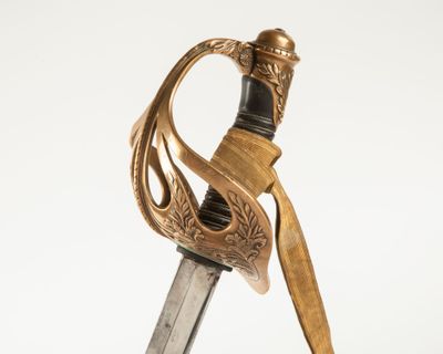 une épée dorée à la poignée noire sur fond blanc