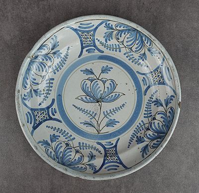 une vieille assiette bleue et blanche ornée d'un motif floral
