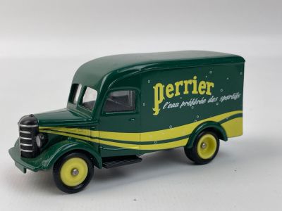 un petit camion vert avec des roues jaunes posé sur une surface blanche