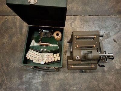 une vieille machine à écrire posée dans un coffret, par terre