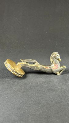 an antique brass figurine of a horse with a bell