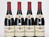 quatre bouteilles de vin rouge sont alignées sur une table