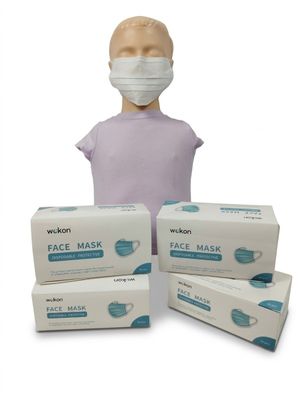 une personne portant un masque à côté de trois boîtes de masques jetables