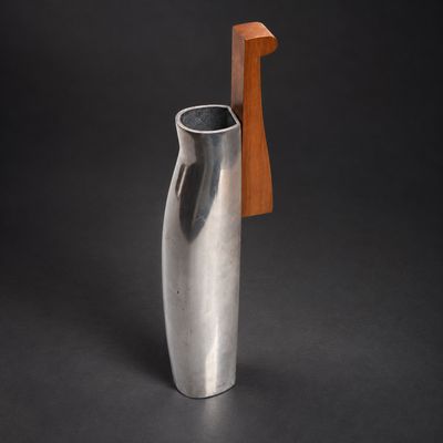 un vase en argent muni d'une poignée en bois, sur fond noir