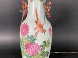 a vase with a bird and flowers on it on a table