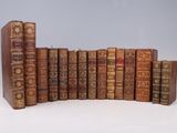 several old books are lined up in a row on a white surface