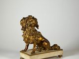 une statue antique en bronze représentant un lion, posée sur un socle en marbre