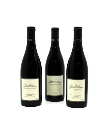 three bottles of wine are lined up on a white surface