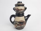 a black and white teapot with a painting on it