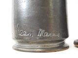 a silver vase with a black lid sitting next to a pair of brown shoes
