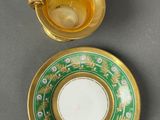 an antique tea cup and saucer with a gold rim and a green and white plate