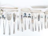 a lot of silver spoons and knives on the table