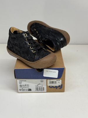 une paire de chaussures noires pour enfants posée sur une boîte en carton