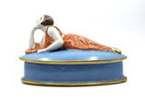 a figurine of a woman laying on top of a blue box