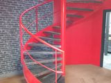 a red spiral staircase in a room with a brick wall