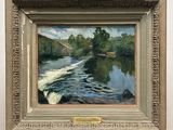 an oil painting of a river in a frame on a wooden stand