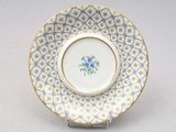 a plate with a blue flower on it on a stand