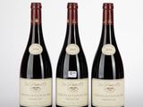trois bouteilles de vin rouge posées côte à côte sur une table
