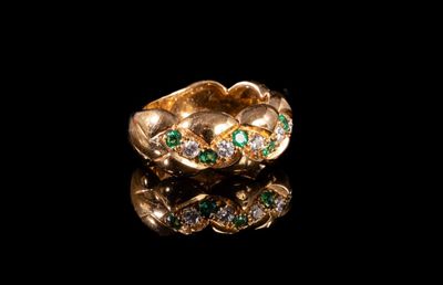 gros plan d'une bague en or avec des pierres vertes et blanches