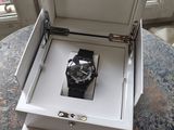une montre dans un coffret, posée sur une table près d'une fenêtre