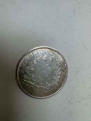 une pièce d'argent posée sur une surface blanche, avec un petit trou au milieu