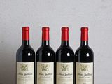 three bottles of wine sit on a wooden table next to a bottle of wine