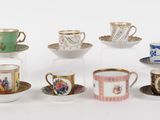 several cups and saucers are lined up on a white surface