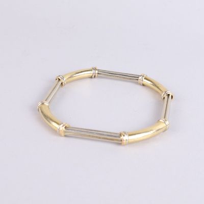 gros plan d'un bracelet en or et en argent sur une surface blanche