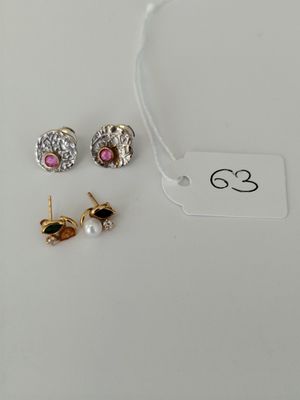 two pairs of earrings and a tag on a white surface