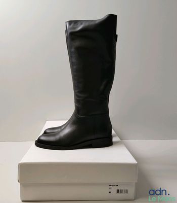 black leather boots on top of a white box on a white surface