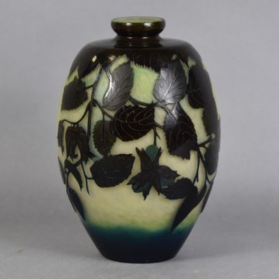 a black and green vase with leaves painted on it