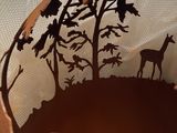 a paper cut of a bird and a deer in the woods