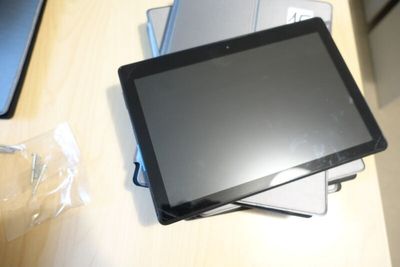 a tablet computer sitting on top of a stack of laptops
