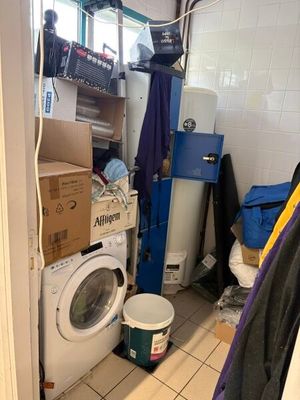 une machine à laver et un sèche-linge dans une pièce où il y a beaucoup de cartons par terre