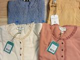 three pairs of women ' s shirts with tags on them on a table