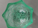 a green glass bowl with a flower inside of it