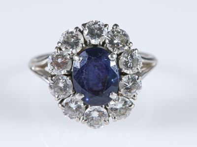 un gros plan d'une bague en saphir et diamants posée sur une surface blanche