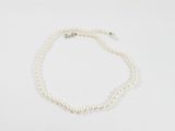 un collier de perles blanches avec un fermoir en argent sur fond blanc