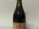 une vieille bouteille de vin posée sur une table blanche