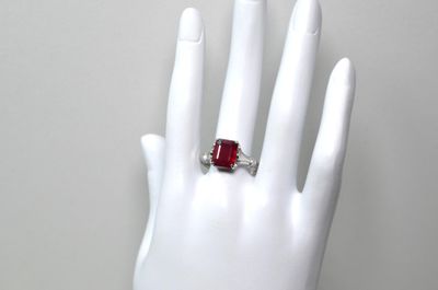 une image représentant la main d'une femme tenant une bague sertie d'une pierre rouge
