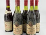 four bottles of wine are lined up on a white surface