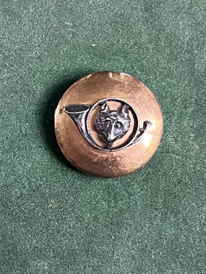 une photo d'un petit bouton en métal sur lequel est représenté un chien